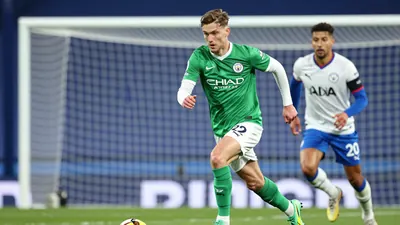 A tight action crop of an anonymous Swansea City player in a green jersey with white sleeves, white shorts, and green...