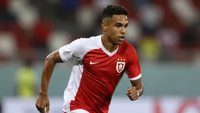 A Brazilian winger in a red and white jersey, mid-dribble, with a focused expression