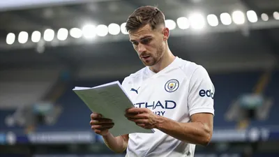 A mid-30s anonymous Swansea City winger, waist-up, wearing a solid white kit, looking focused as he checks a scouting report;
