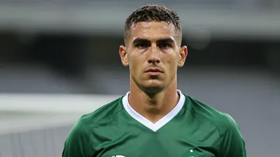 Mid-30s muscular forward, head-and-shoulders, intense gaze, dark green shirt with white collar and sleeves, plain cotton...